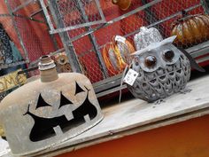 two metal owls sitting on top of a shelf next to pumpkins and other decorations