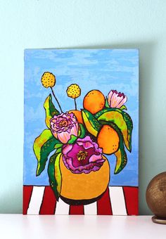 a painting of oranges and flowers in a yellow vase on a table next to a wooden block