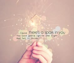 someone holding a sparkler with the words cause there's a spark in you