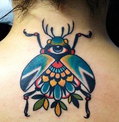 the back of a woman's neck with a colorful beetle tattoo design on it