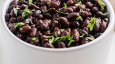 a white bowl filled with black beans and herbs