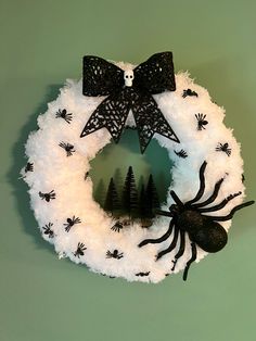 a white wreath decorated with black spider decorations