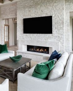 a living room filled with white furniture and a flat screen tv mounted on the wall