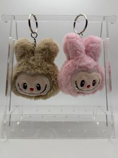 two stuffed animals are hanging in a clear display case with key chains attached to them