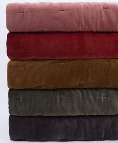 four blankets stacked on top of each other in different colors and sizes, all folded up