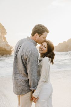 a man and woman standing next to each other on the beach