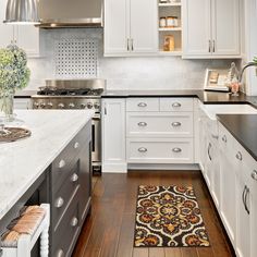 a kitchen with white cabinets and black counter tops, an area rug on the floor