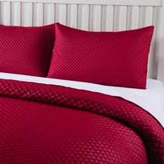 a bed with red sheets and pillows on it