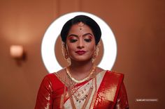 a woman in a red and white sari with gold jewelry on her neck looking at the camera