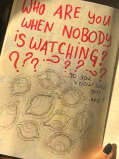 a hand holding up a notebook with writing on it that says who are you when nobody is watching?