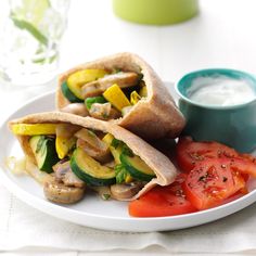 two pita sandwiches on a plate with tomatoes and cucumbers