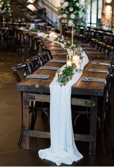 a long table set up with flowers and greenery for an elegant dinner or reception