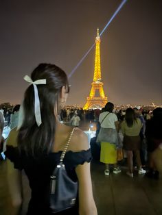 a woman standing in front of the eiffel tower with her back to the camera