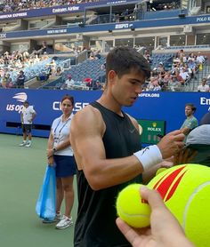 a tennis player is signing autographs for fans on the court while others look on