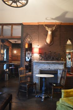 a living room filled with furniture and a deer head mounted to the wall over a fire place