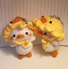 two small crocheted chickens wearing yellow hats and scarfs, one holding a keychain