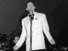 a man in a white suit singing into a microphone