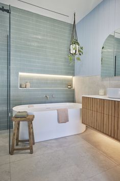 a bathroom with a bathtub, mirror and stool next to the shower area is shown