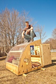 a young man is sitting on top of a wooden structure in the middle of a field