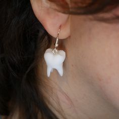 a close up of a person's ear with a tooth shaped earrings on it