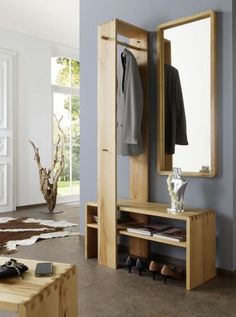 a wooden bench sitting under a mirror next to a coat rack