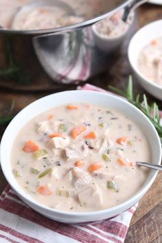 a bowl of chicken and dumpling soup on a table with other dishes in the background