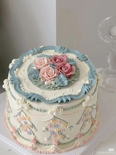 a decorated cake with pink and blue flowers on it's side, sitting on a table