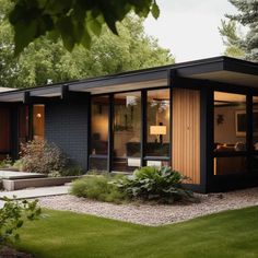 a modern home with black siding and glass doors on the front door is surrounded by lush greenery