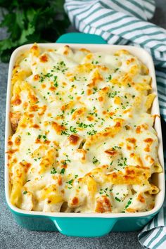 a casserole dish with cheese and parsley in it on a blue plate