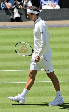 a man walking across a tennis court holding a racquet