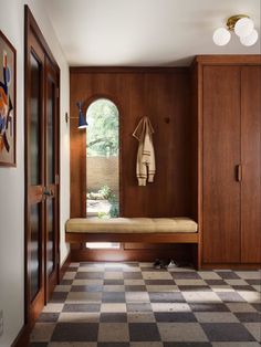 a hallway with a checkered floor and wooden cabinets