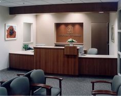 an empty waiting room with chairs in front of the desk and flowers on the wall