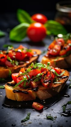 several pieces of bread with tomatoes and basil on top, sitting on a black surface