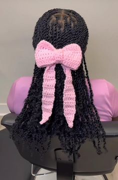 a crocheted hair style with a pink bow on it's head sitting on a black chair