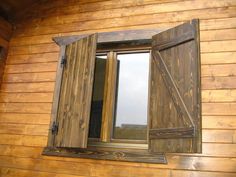 an open window on the side of a wooden building with wood siding and shutters