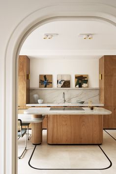 an open kitchen and dining room area with white walls, wood cabinets and marble counter tops