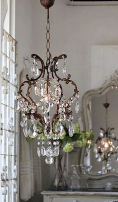 a chandelier hanging from the ceiling in a room with mirrors and vases