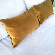 two brown pillows sitting on top of a white bed