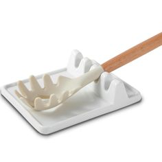 a white spatula with a wooden handle on top of a square plate that is shaped like an alligator's teeth