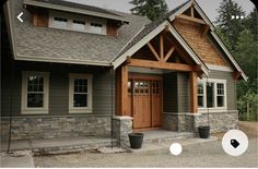 a gray house with wood trim and two large windows on the front door is shown