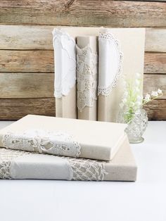 three folded linens are sitting next to each other on a white tablecloth with lace