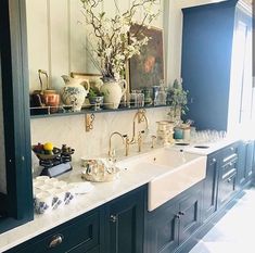 a kitchen with black cabinets and white counter tops, gold faucets and vases on the wall