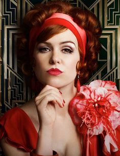 a woman with red hair wearing a headband and holding a flower in front of her face