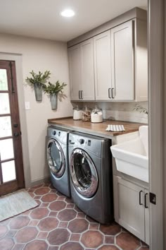 a washer and dryer sitting in a kitchen next to a sink with potted plants on the counter