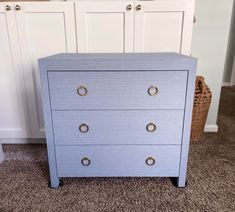 a blue chest of drawers sitting on top of a carpeted floor next to white cabinets