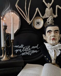 a statue of abraham lincoln next to an open book with candles and skeleton decorations on the wall behind it