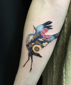 a blue bird with flowers on it's arm is shown in this tattoo design