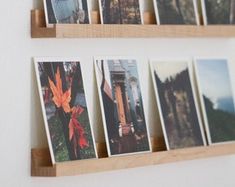 several photographs are hanging on the wall with wooden shelves above them, along with other photos