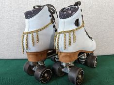 two white roller skates with gold chains on them