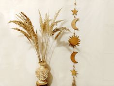 a vase filled with dried grass next to a wall hanging